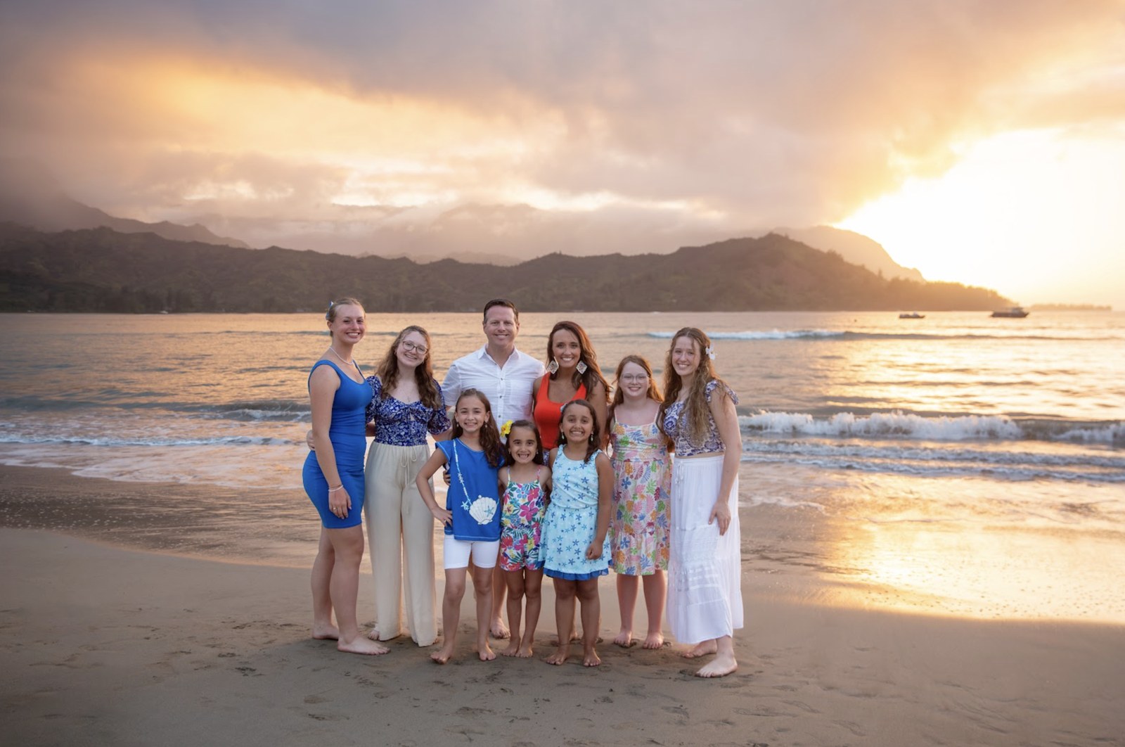 Scott and Andrea Osborn with their seven daughters on a beach at sunset